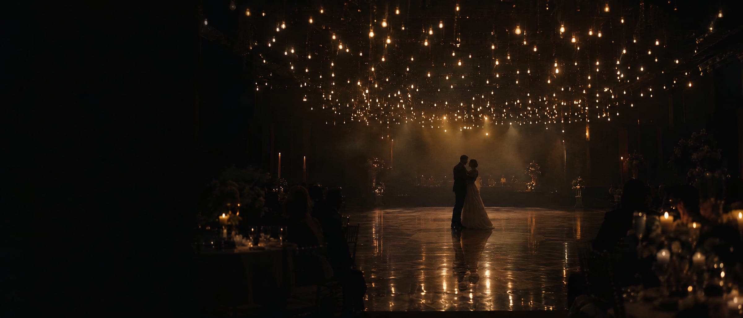 Concept image: a couple dancing beneath a canopy of warm lights in a dark ballroom