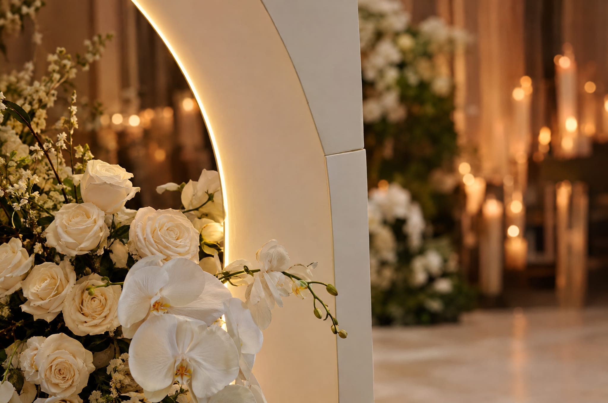 A backlit ivory arch edge with white roses at its base