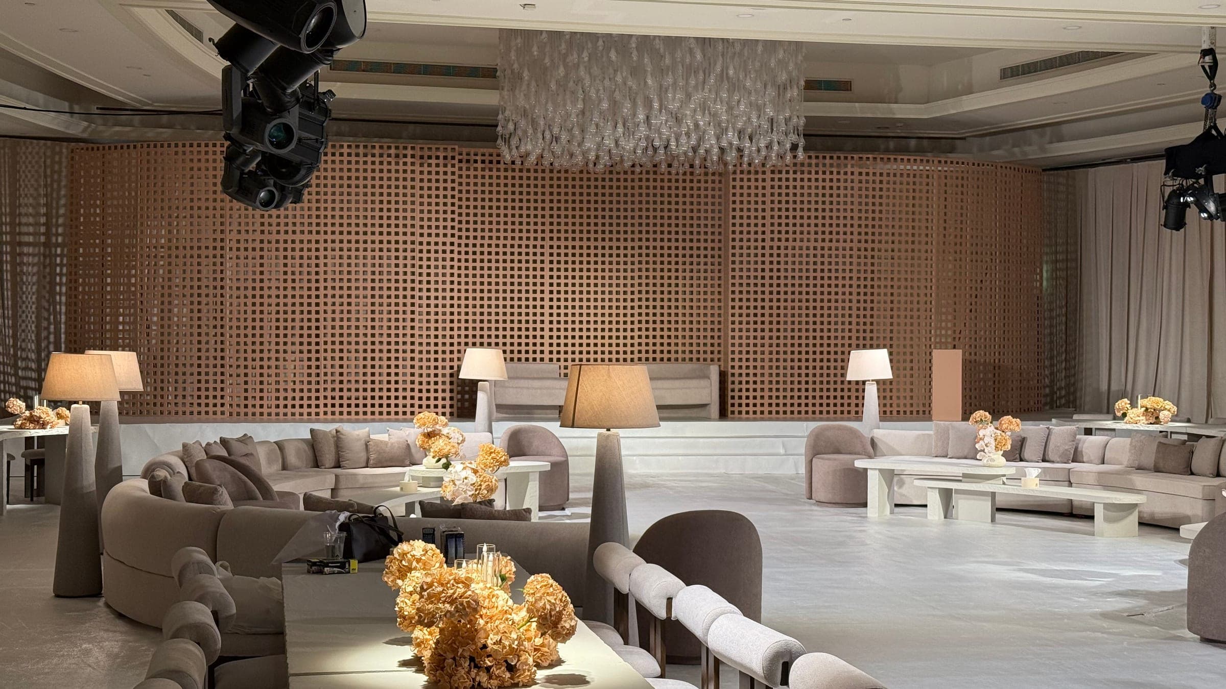 Lounge seating and tables with hydrangeas before a terracotta lattice wall and a suspended crystal installation
